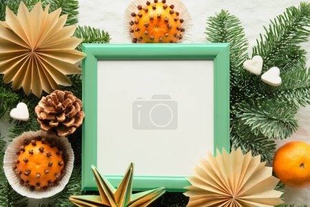 Photo for Fragrant pomander balls handmade from tangerines with cloves. Handmade paper stars from brown paper. Flat lay on off white textile with fir twigs. Copy-space, text place in square white green frame. - Royalty Free Image