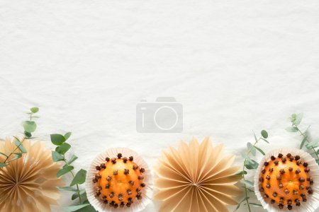 Photo for Christmas border, copy-space. Fragrant pomander balls handmade from tangerines with cloves. Handmade stars from brown baking paper. Panoramic flat lay on off white textile tablecloth with eucalyptus. - Royalty Free Image