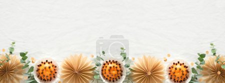 Photo for Christmas border, copy-space. Fragrant pomander balls handmade from tangerines with cloves. Handmade stars from brown baking paper. Panoramic flat lay on off white textile tablecloth with eucalyptus. - Royalty Free Image