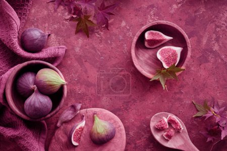 Photo for Panoramic banner Autumntime background with fresh halved fig fruits. Dry eucalyptus and cala lily flowers painted metallic pink on dark brown background. - Royalty Free Image