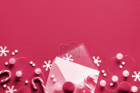 Foto de Viva Magenta color del año 2023. Tarjetas de felicitación de Navidad con bastones de caramelo en sobres de papel. Fondo de Navidad con bastones de caramelo, vibrantes baratijas magenta, copos de nieve. Vista superior, plano, copia-espacio. - Imagen libre de derechos