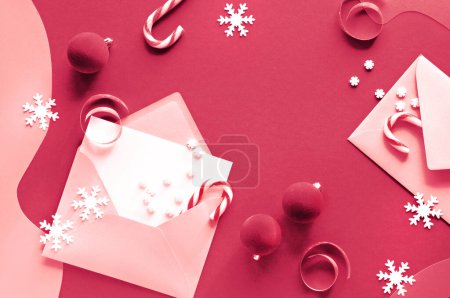 Photo for Viva Magenta color of the year 2023. Christmas greeting cards with candy canes in paper envelopes. Xmas background with candy canes, vibrant magenta trinkets, snowflakes. Top view, flat lay on paper. - Royalty Free Image