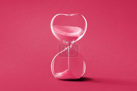 Photo for Hourglass, toned monochrome image in Viva Magenta color of the year 2023. Sandglass or sand timer. Single sand clock with golden sand on vibrant paper background. Design element, - Royalty Free Image