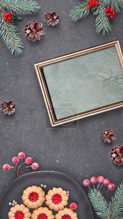 Photo for Flat lay with Xmas decorations in green and red and jam cookies. Flat lay, top view on dark table. Copy-space, text place in golden frame. - Royalty Free Image
