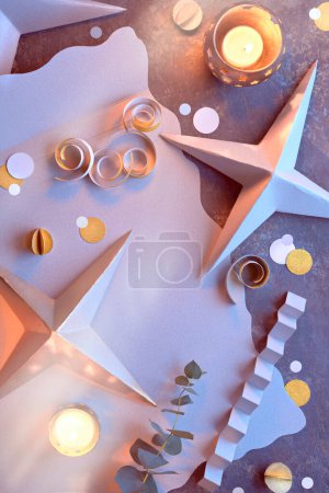Foto de Decoraciones hechas a mano de Navidad o Año Nuevo de cartón. Vista superior, plano con luces en la guirnalda de Navidad, bolas de papel dorado, copos de nieve, eucalipto. Feliz Navidad, feliz año nuevo fondo. - Imagen libre de derechos