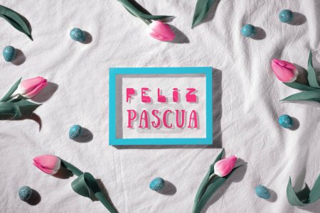 Photo for Easter background, pink tulip flowers and quail eggs. Decorated background with blackboard. Text Feliz Pascua means Happy Easter in Spanish language. Top view, flat lay, springtime decor in pink, off white and turquoise colors. - Royalty Free Image