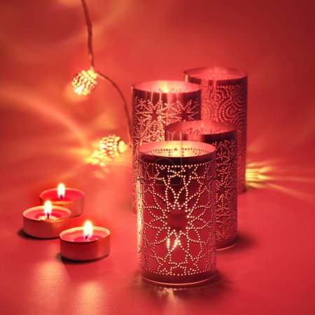 Photo for Oriental metal lanterns and tea lights. Viva magenta, color of the year 2023. Red background lit by candlelight in vivid red and golden colors - Royalty Free Image