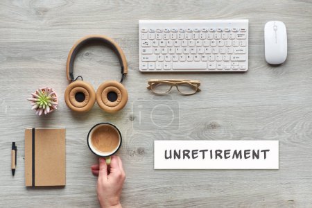 Photo for Unretirement concept image. Flat lay with modern office supplies - notebook, computer keyboard, mouse, succulent plant. Paper with text, caption Unretirement. Hand of mature worker holding coffee. - Royalty Free Image