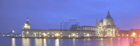 Photo for Illuminated Punta della Dogana and church Santa Maria della Salute in Venice, Italy. Panoramic image taken in the evening. - Royalty Free Image