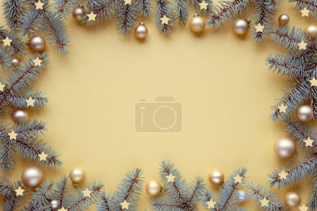 Photo for Christmas frame with fir twigs and golden baubles, trinkets. Copy-space, place for your text, greeting, caption. Top view, flat lay, festive Xmas background on gold yellow metallic paper. - Royalty Free Image