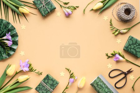 Photo for Spring freesia and tulip flowers and gift boxes. Golden yellow background with green wrapping paper, scissors and cord. Flat lay, top view with copy-space. Orange, green, purple pastel colors. - Royalty Free Image