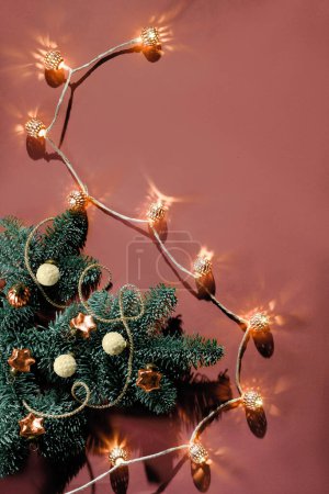 Foto de Christmas decorations, baubles, cones and ribbons on natural fir twig. Xmas background on orange brown paper with electric light garland. Flat lay, top view with copy-space, place for text overhead. - Imagen libre de derechos