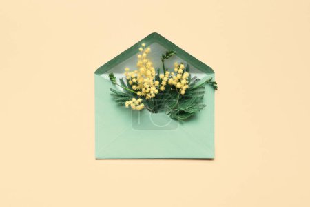 Téléchargez les photos : Fresh mimosa flowers in green paper envelope, flat lay, top view on pale yellow background. Springtime greeting design for birthday, spring invitation, March 8 International Women's Day. - en image libre de droit