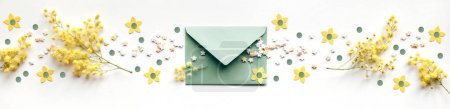Photo for Panorama with fresh mimosa flowers around mint green envelope, sugar sprinkles, paper flowers. Panoramic banner with natural springtime decor in yellow and pale mint green. Flat lay, top view,. - Royalty Free Image
