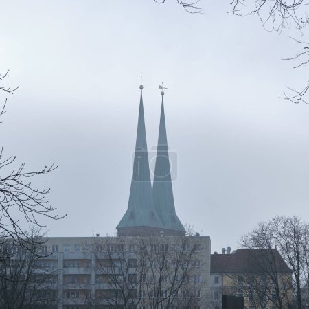 Photo for Two steeples of St. Nicholas, or Nicolai Church, or Nikolaikirche in German language in the historic district of Berlin Germany covered in mist - Royalty Free Image