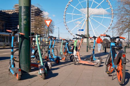 Photo for BRUSSELS, BELGIUM - FBERUARY 26, 2023: A group of scooters parked in front of a ferris wheel. - Royalty Free Image