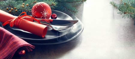Téléchargez les photos : Concept de menu de Noël avec assiettes noires et couverts au décor festif. Espace de copie, lieu de texte. - en image libre de droit