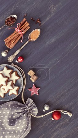 Photo for Christmas background in grey, white and red on dark wood. A table topped with a plate of cookies next to a bag of cookies. - Royalty Free Image