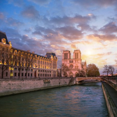 Téléchargez les photos : Notre-Dame à Paris et au bord de la rivière au coucher du soleil avec des nuages de plumes roses et violettes. - en image libre de droit
