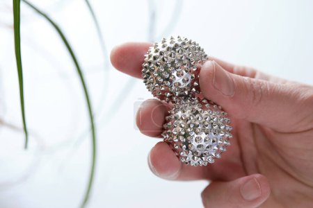 Téléchargez les photos : Balles magnétiques en métal argenté pour massage des mains à la main féminine, gros plan. - en image libre de droit