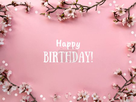 Photo for Text Happy Birthday in a frame with blossoming spring almond flowers on a pink paper background. - Royalty Free Image