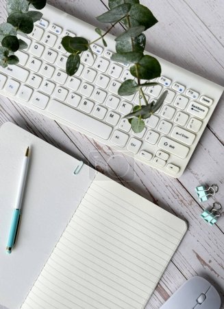 Foto de Una foto que muestra un teclado de computadora estándar, un cuaderno en blanco y un ratón con cable arreglado cuidadosamente en un escritorio. - Imagen libre de derechos