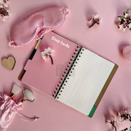 Photo for Square pink overhead background, quality of sleep, and self care routine. Sleeping mask, notebook with words sleep hacks, massage stone roller, cream and wooden heart on pink paper. - Royalty Free Image