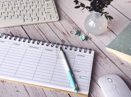 Foto de Un escritorio con un planificador semanal en blanco, teclado, ratón, y un cuaderno para el trabajo productivo. - Imagen libre de derechos