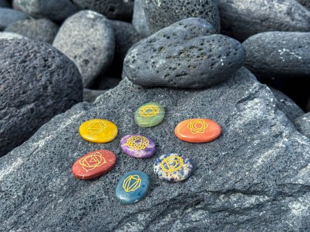 Photo for Healing crystals, chakra stones. Rainbow gemstones in a circle on grey volcanic pebbles. - Royalty Free Image