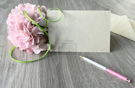 Foto de Una foto que muestra una flor rosa y un bolígrafo colocado en una mesa. Copia-espacio en la tarjeta de felicitación en blanco. - Imagen libre de derechos