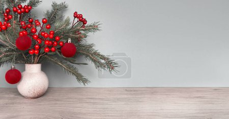 Winterliches Arrangement mit Tannenzweigen, Weihnachtsdekoration und roten Vogelbeeren auf dem Holztisch neben der grauen Wand. Panoramabild, Kopierraum.