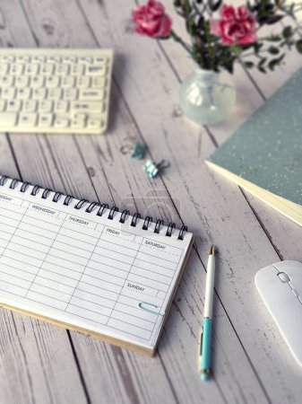 Photo for This photo showcases a desk featuring a blank weekly planner, keyboard, mouse, and notebook placed neatly, ready for work or study. - Royalty Free Image
