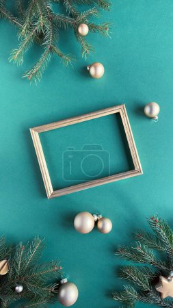 A vibrant green background decorated with festive holiday ornaments. The display includes fir twigs, gold baubles, and other Christmas decorations around blank golden frame.