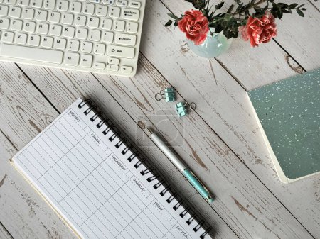 Foto de Un escritorio con un planificador semanal en blanco, teclado de computadora y un bloc de notas en la parte superior, listo para el trabajo o el estudio. - Imagen libre de derechos