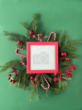 A festive Christmas frame with copy-space adorned with Xmas decor - fir twigs, rowanberries, and baubles, creating a cheerful holiday atmosphere.