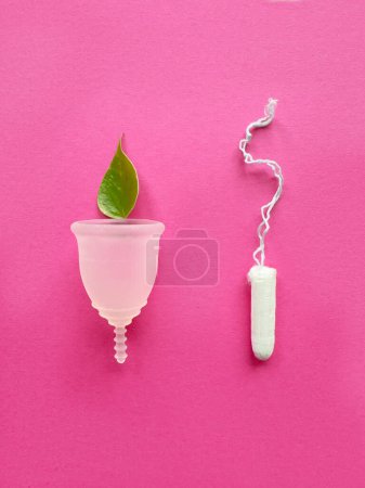 Téléchargez les photos : Coupe menstruelle en silicone réutilisable et tampon standard sur fond papier magenta, vue aérienne - en image libre de droit