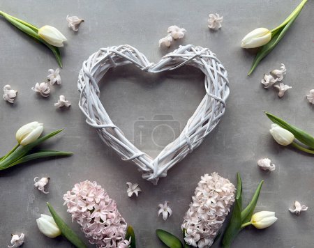 Téléchargez les photos : Une couronne en forme de cœur avec des fleurs printanières, y compris des tulipes et jacinthe, avec un papillon en céramique colorée. - en image libre de droit