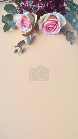 Photo for Pale pink roses and eucalyptus twigs, toned apricot colored background with copy-space, simple floral background - Royalty Free Image
