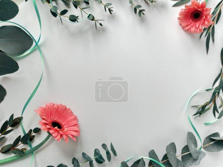 Téléchargez les photos : Fond blanc avec fleurs de gerbera roses, eucalyptus, diverses brindilles persistantes, vue aérienne. - en image libre de droit