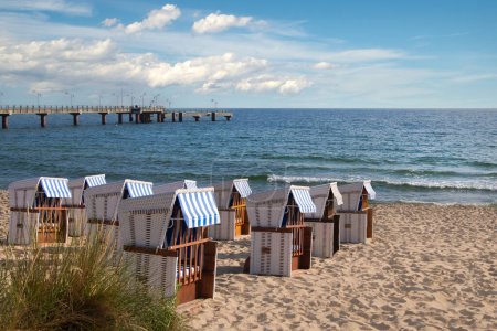 Téléchargez les photos : Une rangée de chaises longues alignées sur une plage de sable sous le soleil. Rivages romantiques de la mer Baltique. - en image libre de droit