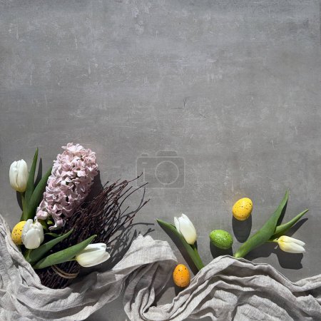 Photo for A colorful Easter composition with spring flowers, including tulips, arranged in a bouquet resting on top of a grey stone table, copy-space - Royalty Free Image