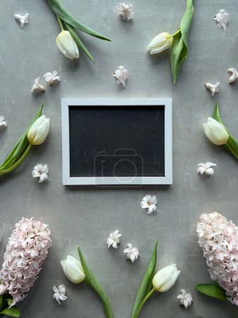 Foto de Un marco de pizarra en blanco rodeado de una variedad de flores de tulipán de primavera y jacinto. - Imagen libre de derechos
