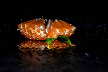 Photo for Cut tangerine with splashes of water on a black background - Royalty Free Image
