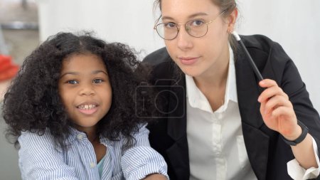 Foto de African American black girl having fun smiling high five with Caucasian teacher international diversity school environment - Imagen libre de derechos