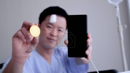 Foto de Hombre asiático mostrando cripto y teléfono inteligente accidente lesionar la gestión de riesgos de inversión saludable - Imagen libre de derechos