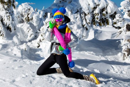 Photo for Winter fashion. Beautiful girl is wearing jacket, ski goggles and colorful winter hat and is posing on mountains background. Szrenica, Poland. Mountain travel. - Royalty Free Image