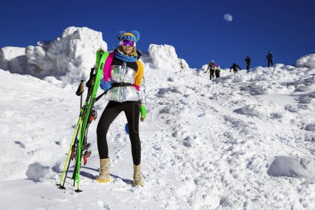 Téléchargez les photos : Fille skieuse aime la station de ski. Belle femme en tenue d'hiver pose avec des skis dans les montagnes. Sports d'hiver. Ski de fond. - en image libre de droit