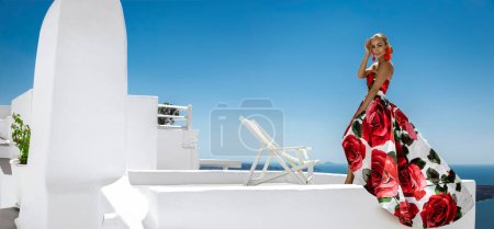 Téléchargez les photos : Belle femme élégante en robe longue à fleurs pose dans un complexe de luxe à Santorin. Modèle féminin en robe longue incroyable. - en image libre de droit