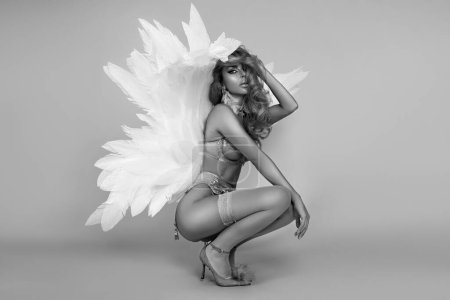 Foto de Hermosa mujer rubia sexy en lencería elegante y alas de ángel está posando sensualmente en el estudio. Angel en lencería, foto artística en blanco y negro - Imagen libre de derechos