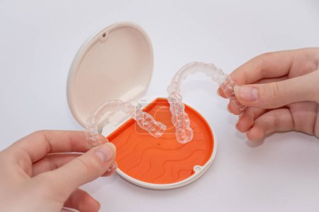 Transparent aligners retainers in a storage case. Invisible braces. Clear teeth straighteners. Plastic bracers